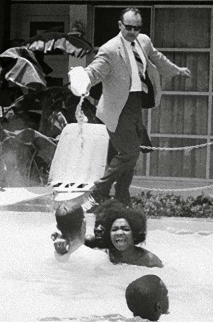 Em 1964, um gerente de hotel derrama ácido na piscina, enquanto várias pessoas negras estão nadando.