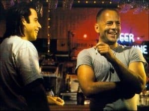 John Travolta e Bruce Willis rindo enquanto descansam para a próxima cena.